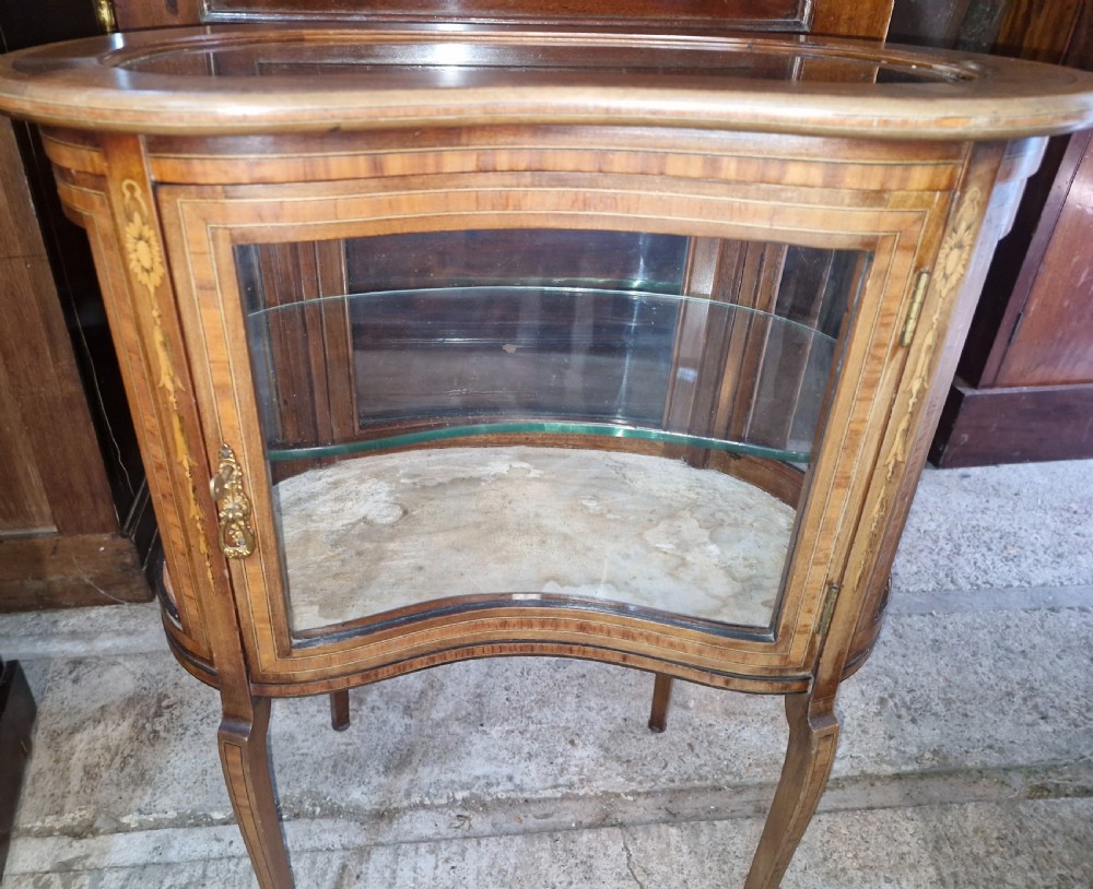 An Edwardian kidney-shaped mahogany bijouterie display cabinet featuring glass panels, marquetry inlay, and cabriole legs. View VIII