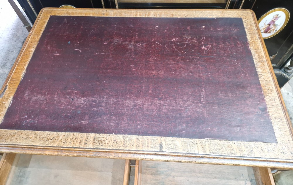 A Victorian oak writing table featuring an inset leather writing surface, two frieze drawers, turned legs, and brass castors. View III