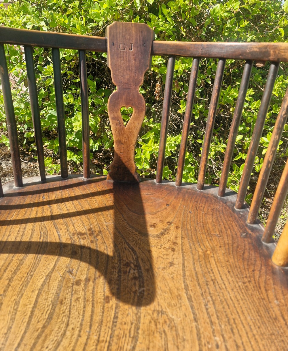 A mid 19th-century wooden Windsor desk armchair with a shaped saddle seat, spindle back with carved heart central splat, and turned legs. View II