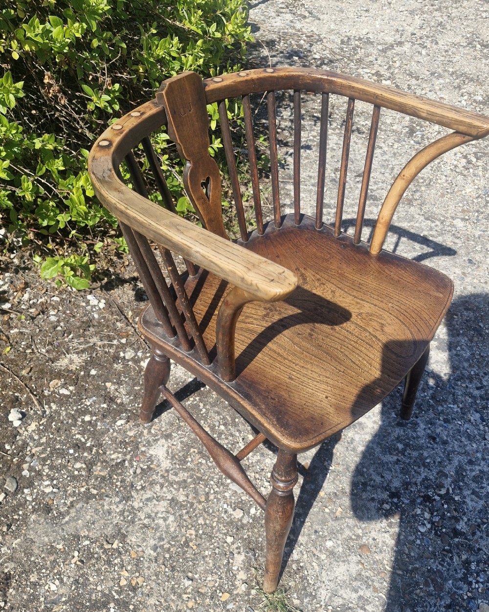A mid 19th-century wooden Windsor desk armchair with a shaped saddle seat, spindle back with carved heart central splat, and turned legs. View III