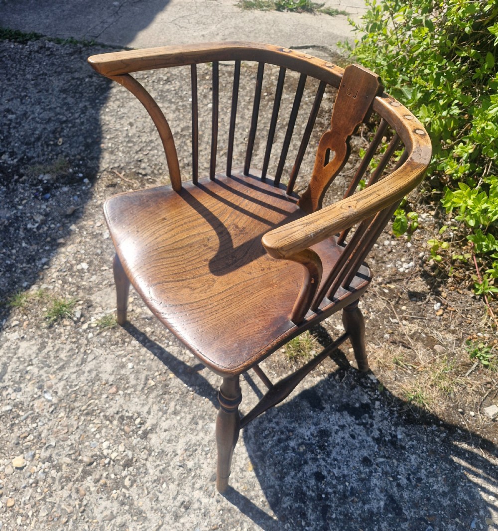 A mid 19th-century wooden Windsor desk armchair with a shaped saddle seat, spindle back with carved heart central splat, and turned legs. View V