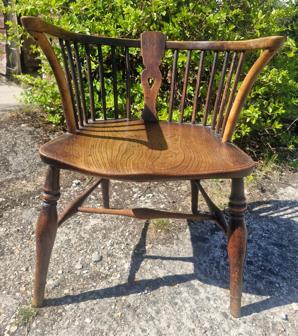 A mid 19th-century wooden Windsor desk armchair with a shaped saddle seat, spindle back with carved heart central splat, and turned legs. View VI