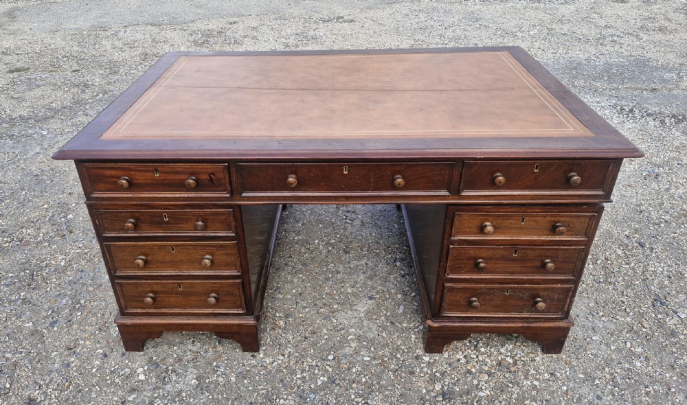 A Victorian mahogany twin pedestal partners desk featuring a brown leather writing surface with gold tooling and turned wooden handles.