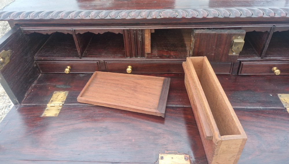A four-drawer dark rosewood Anglo-Indian campaign secretaire chest featuring recessed brass handles, diamond escutcheons, and carved gadrooned borders. View V