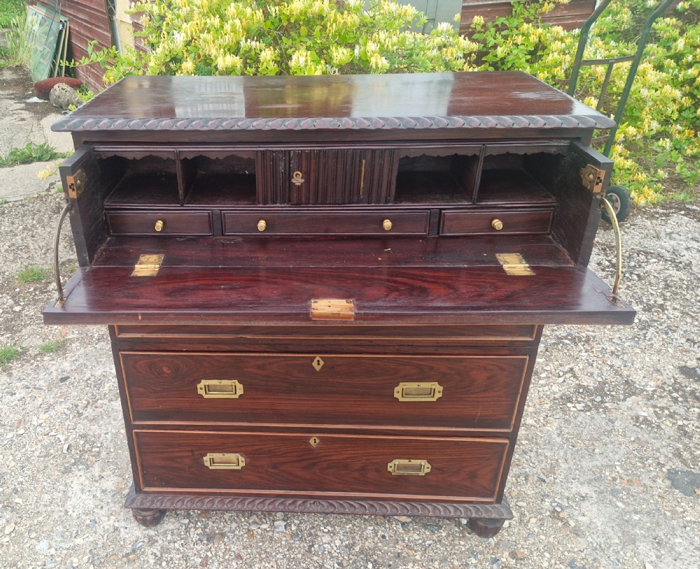 A four-drawer dark rosewood Anglo-Indian campaign secretaire chest featuring recessed brass handles, diamond escutcheons, and carved gadrooned borders. View VI
