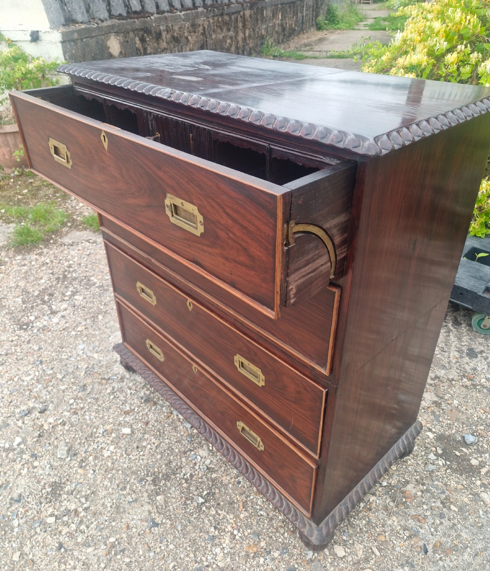 A four-drawer dark rosewood Anglo-Indian campaign secretaire chest featuring recessed brass handles, diamond escutcheons, and carved gadrooned borders. View X