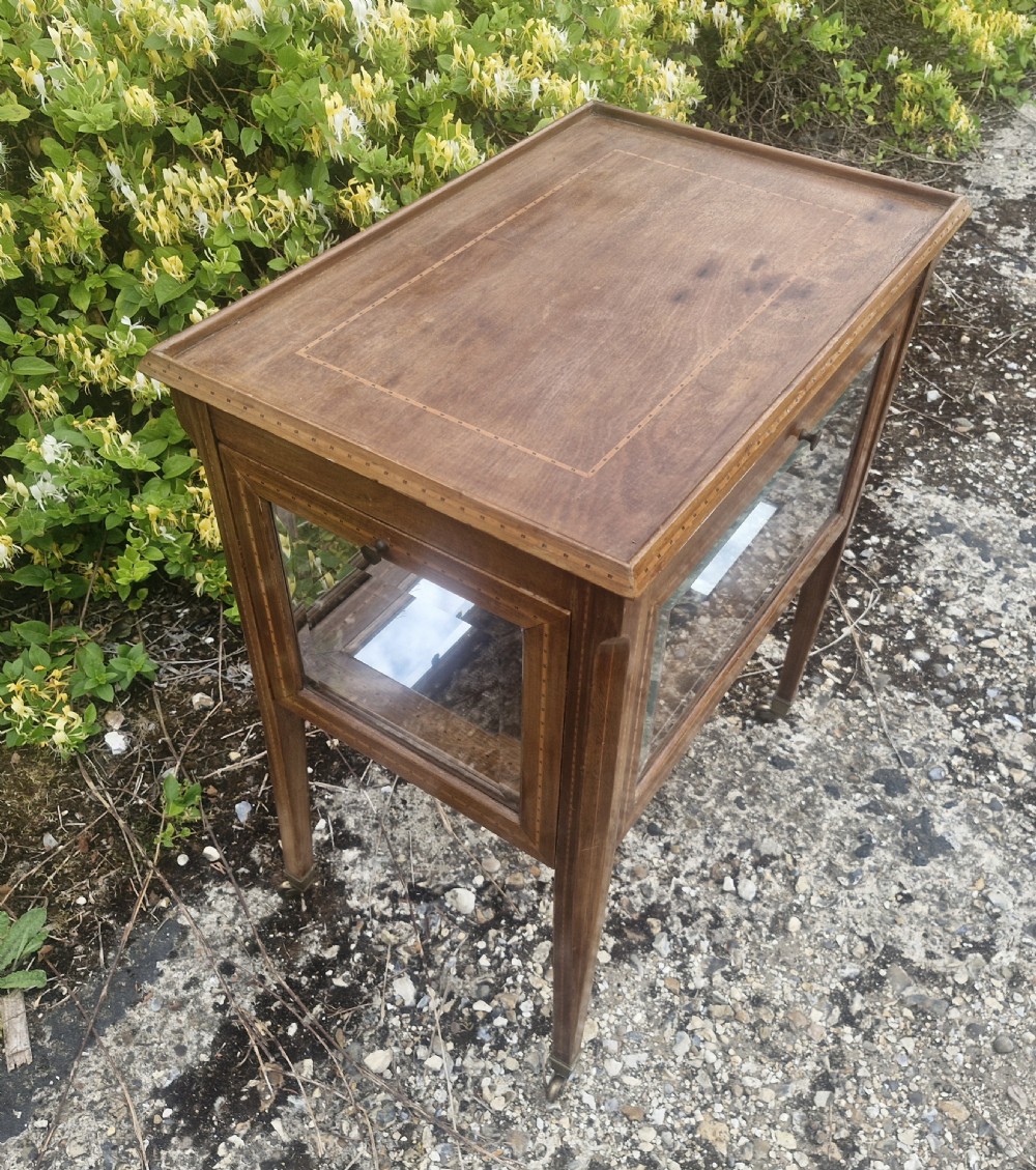 An Edwardian mahogany tea trolley featuring drop-down glazed side panels, satinwood string inlay, tapered legs, and small brass castors. View III