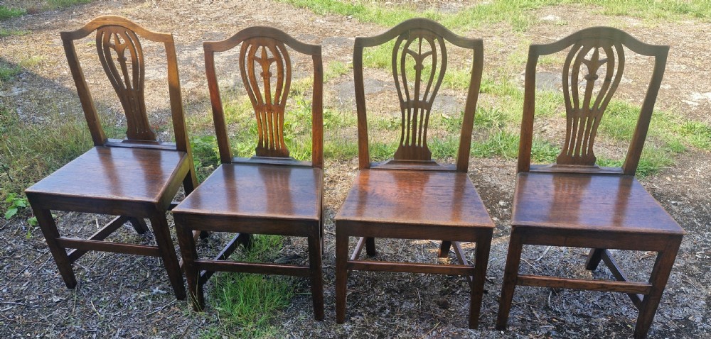 Set of four early nineteenth-century country dining chairs crafted from dark wood with pierced balloon splat backs and solid seats.
