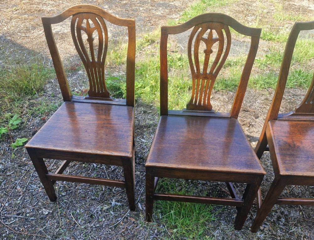 Set of four early nineteenth-century country dining chairs crafted from dark wood with pierced balloon splat backs and solid seats. View II