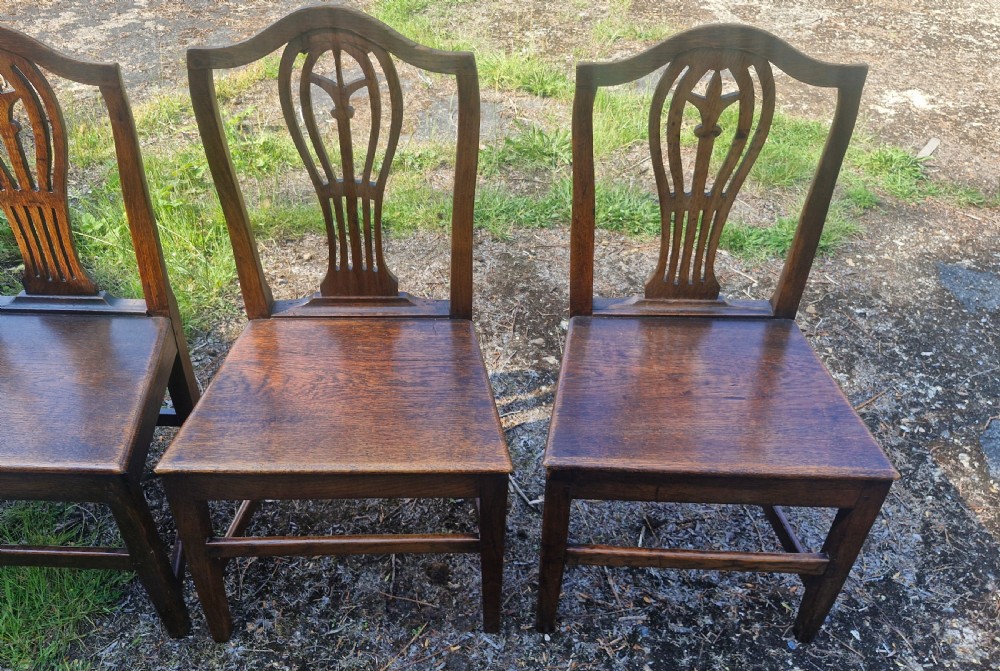 Set of four early nineteenth-century country dining chairs crafted from dark wood with pierced balloon splat backs and solid seats. View V