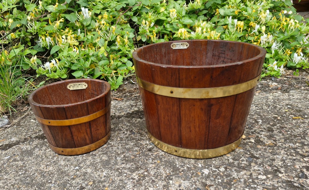 A pair of graduated tapered wooden planters constructed with coopered staves and bound with polished brass bands. View II