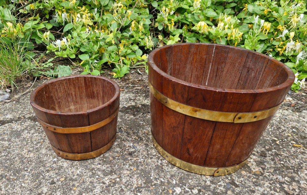 A pair of graduated tapered wooden planters constructed with coopered staves and bound with polished brass bands. View III