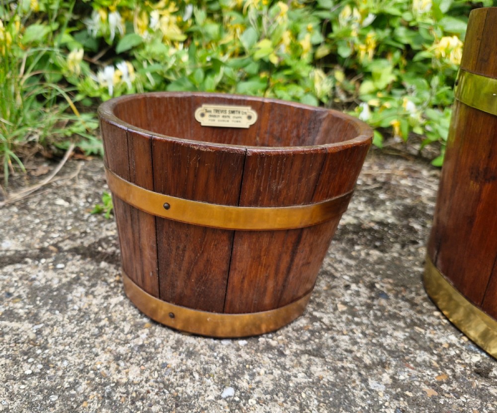 A pair of graduated tapered wooden planters constructed with coopered staves and bound with polished brass bands. View VI
