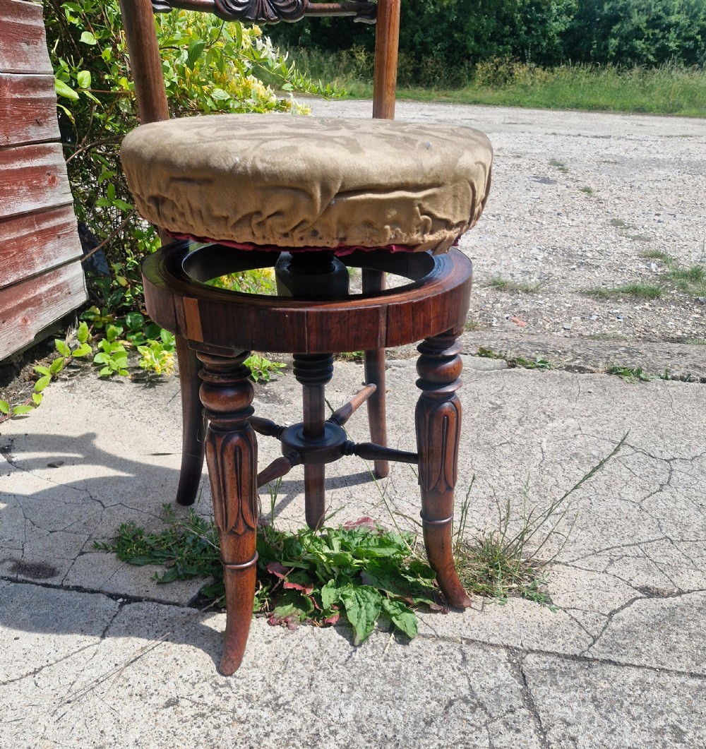 A Regency period dark rosewood adjustable music chair featuring a carved backrest, circular upholstered seat, and turned legs. View VII