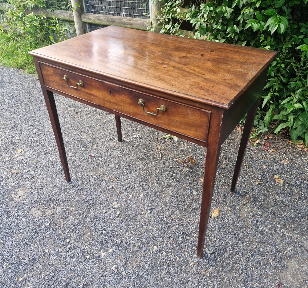 A late Georgian mahogany side table featuring a single long drawer with two brass swan-neck handles and four square tapered legs.