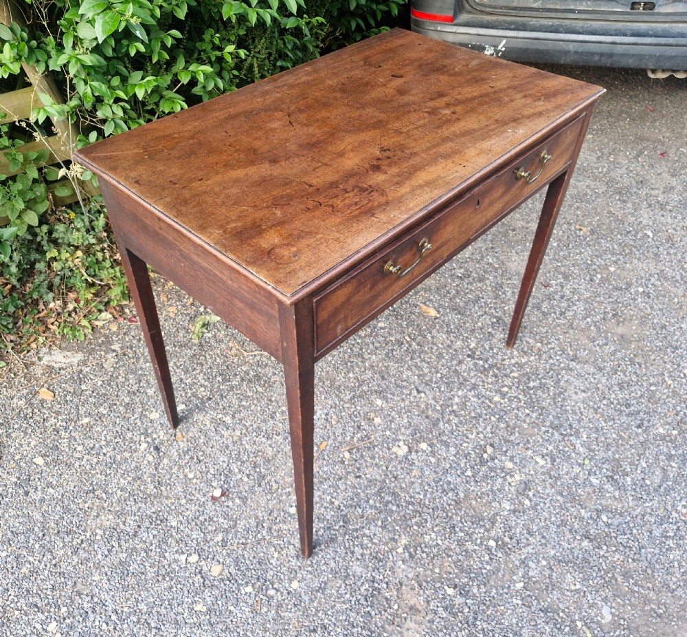 A late Georgian mahogany side table featuring a single long drawer with two brass swan-neck handles and four square tapered legs. View VI