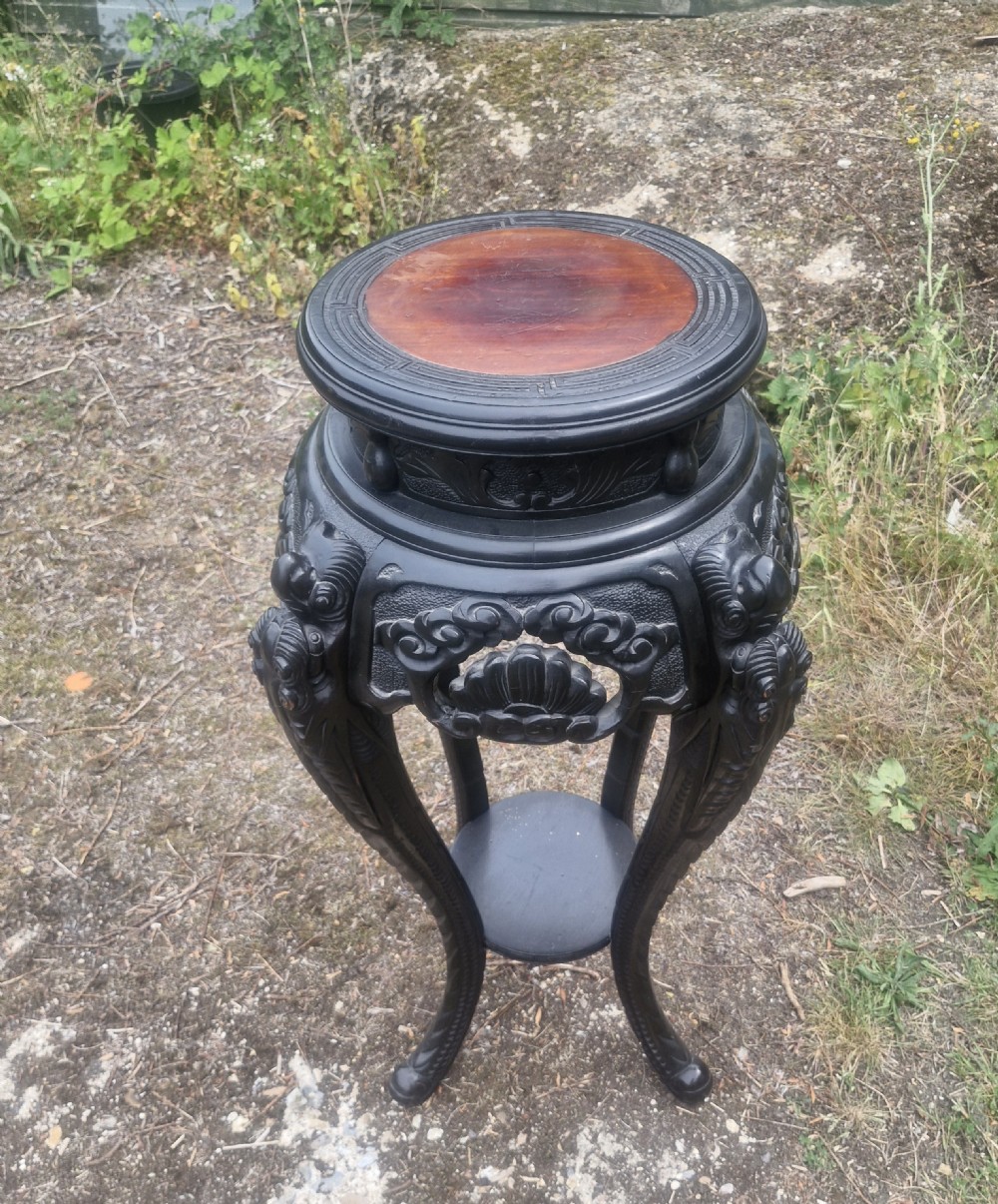 An early 20th-century ebonised hardwood Oriental jardiniere stand with carved aprons, cabriole legs, and a lower shelf. View II