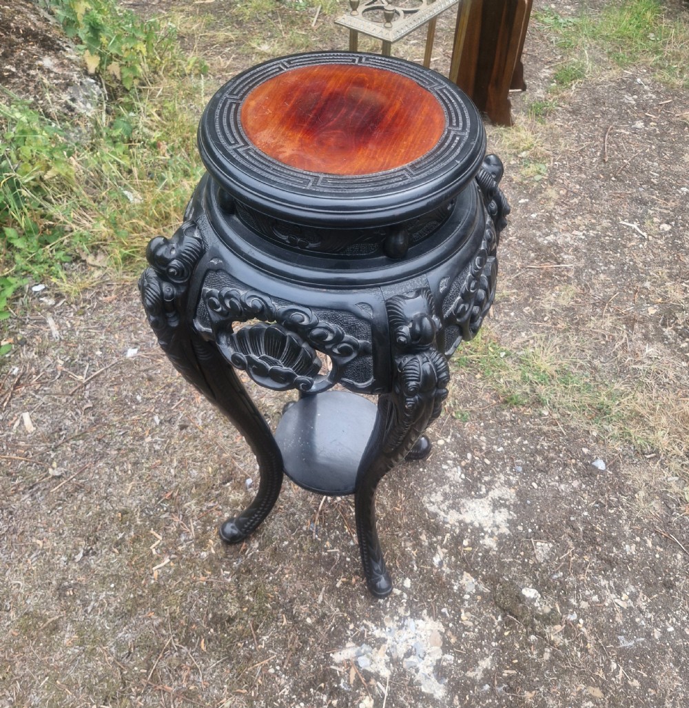 An early 20th-century ebonised hardwood Oriental jardiniere stand with carved aprons, cabriole legs, and a lower shelf. View III