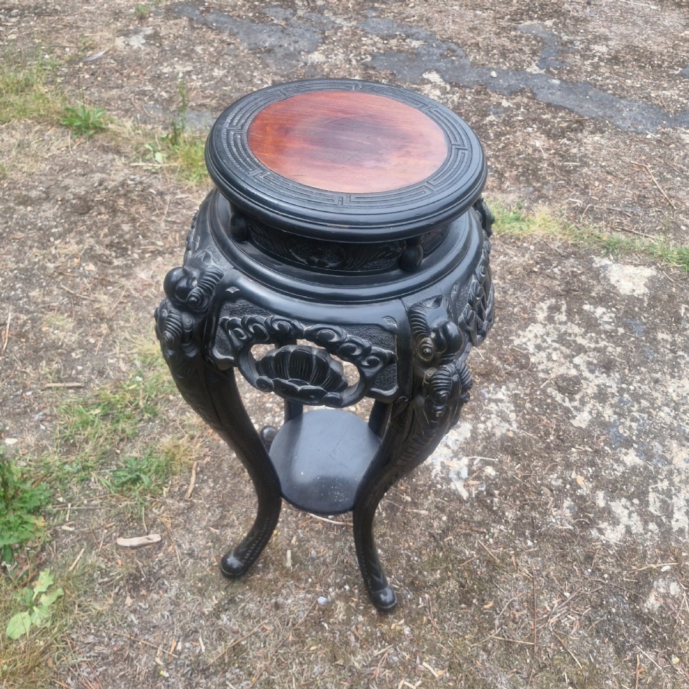 An early 20th-century ebonised hardwood Oriental jardiniere stand with carved aprons, cabriole legs, and a lower shelf. View IV