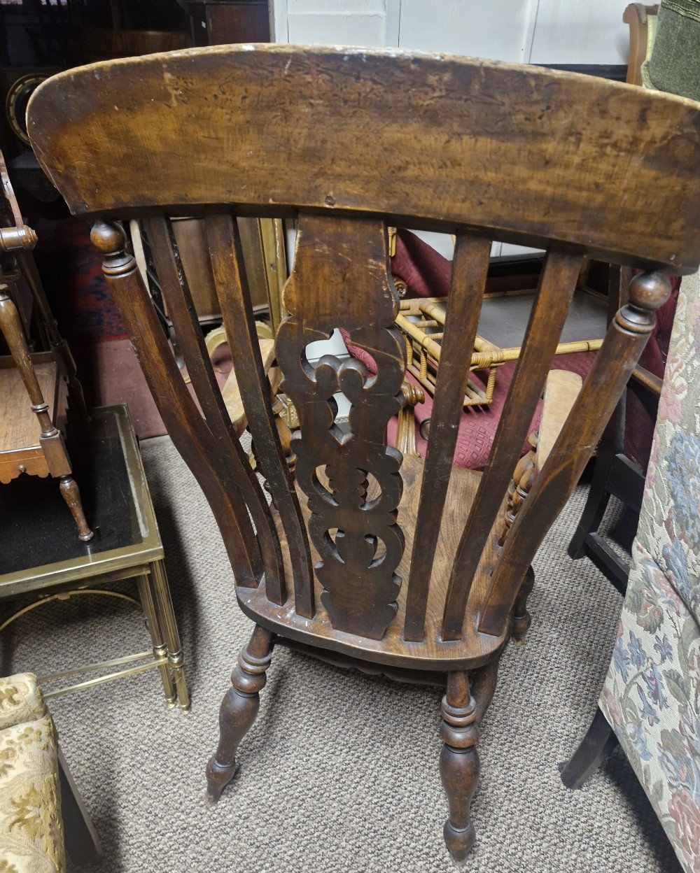 A dark-stained Victorian Windsor armchair with a spindled high back, carved central splat, shaped armrests, solid seat, and turned wooden legs. View XIII
