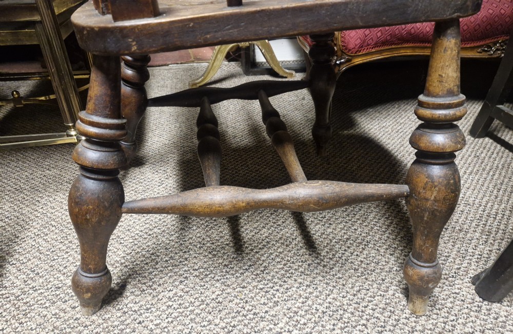 A dark-stained Victorian Windsor armchair with a spindled high back, carved central splat, shaped armrests, solid seat, and turned wooden legs. View XV