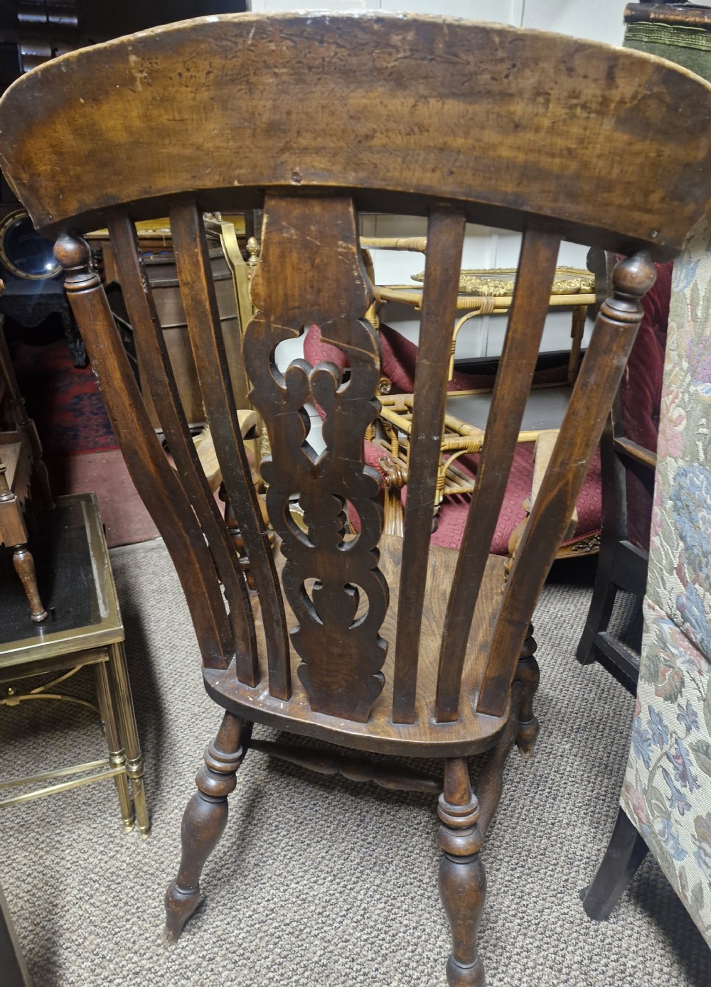 A dark-stained Victorian Windsor armchair with a spindled high back, carved central splat, shaped armrests, solid seat, and turned wooden legs. View XVI