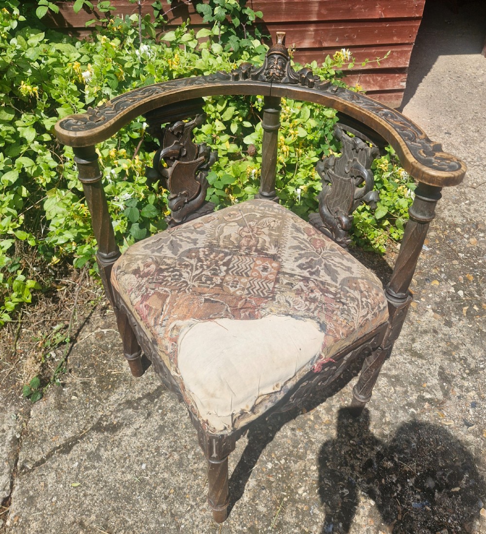 A late 19th-century carved oak corner armchair featuring a curved crest rail with a carved mask detail, turned supports, and a tapestry upholstered seat. View III