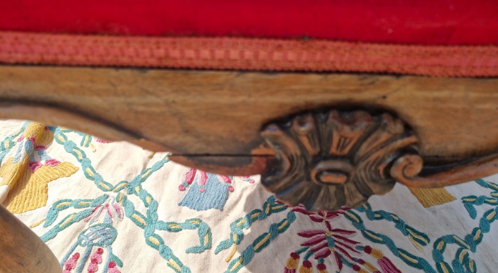 A mid-19th-century carved hardwood centre stool featuring cabriole legs with scroll feet, a decorative floral apron carving, and a crimson red velvet cushion. View VIII