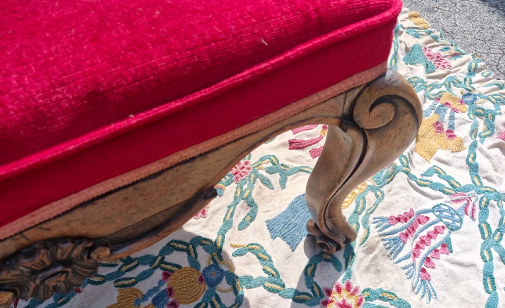 A mid-19th-century carved hardwood centre stool featuring cabriole legs with scroll feet, a decorative floral apron carving, and a crimson red velvet cushion. View IX