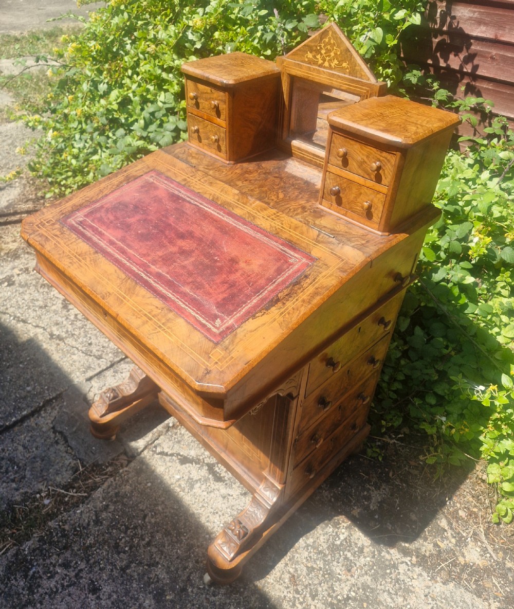 A Victorian burr walnut Davenport desk with a sloped red leather writing surface, inlaid top cresting, and side drawers. View V