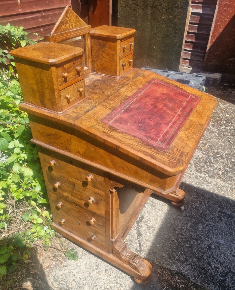 A Victorian burr walnut Davenport desk with a sloped red leather writing surface, inlaid top cresting, and side drawers. View VII