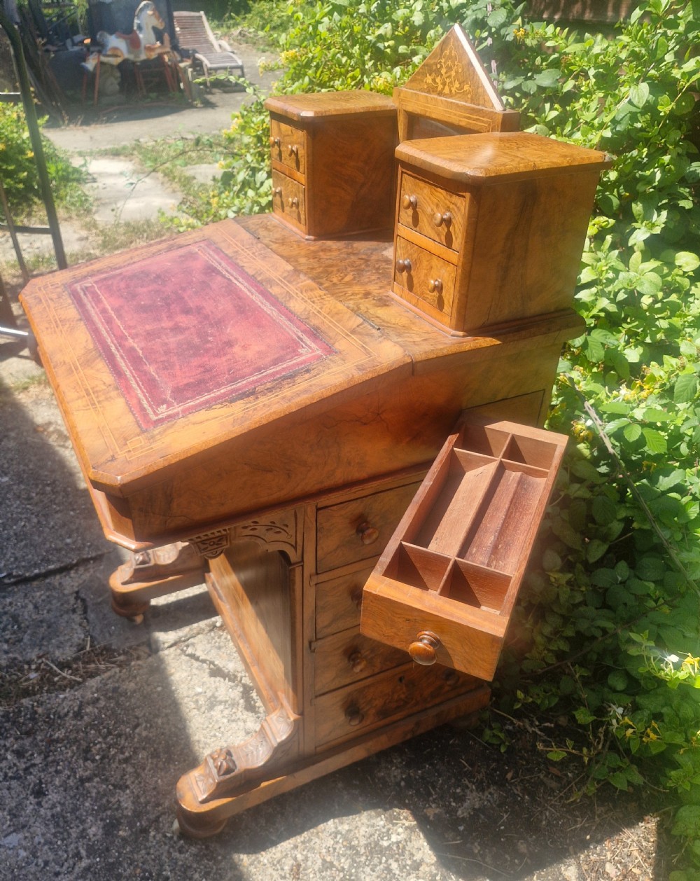 A Victorian burr walnut Davenport desk with a sloped red leather writing surface, inlaid top cresting, and side drawers. View X