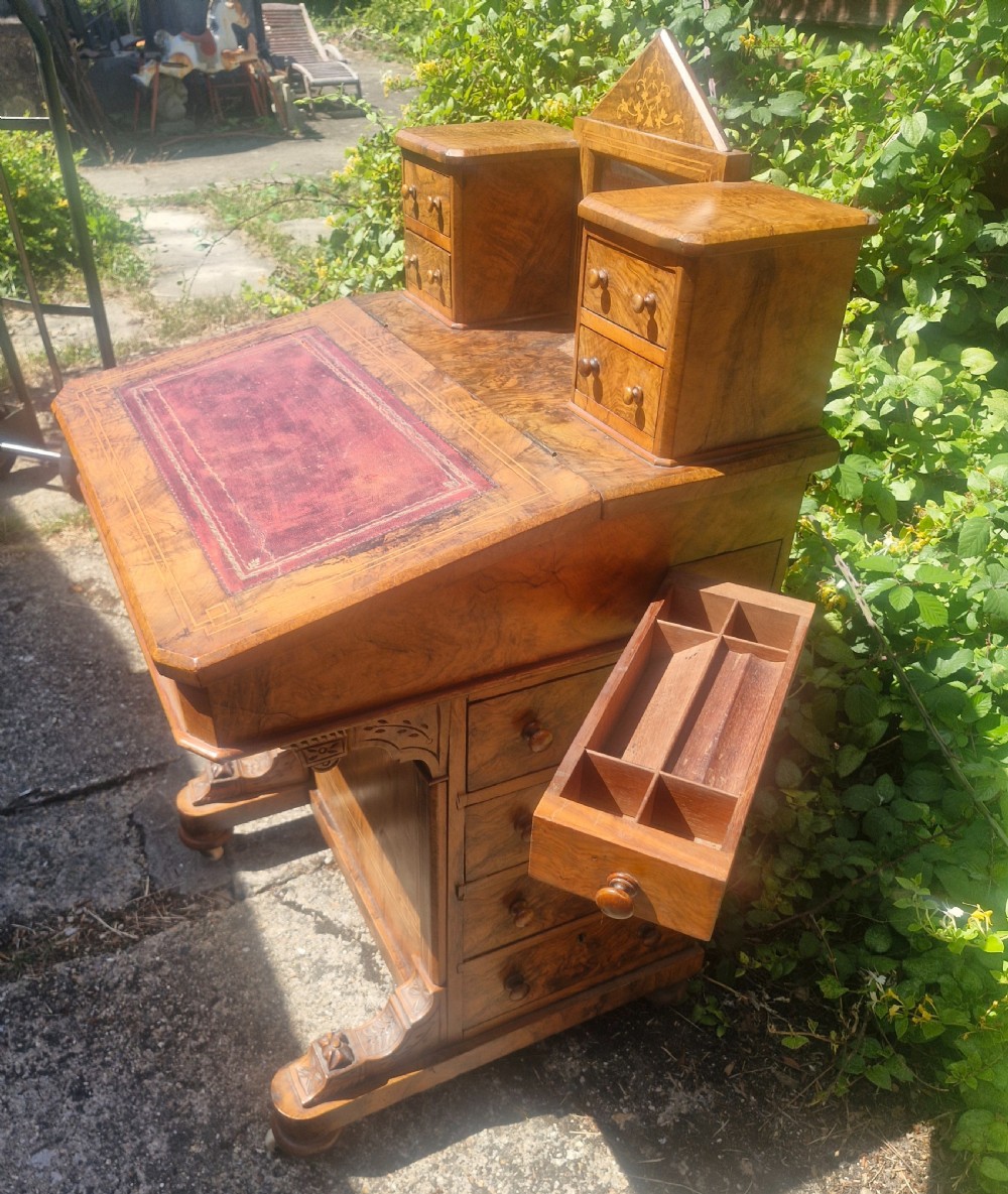 A Victorian burr walnut Davenport desk with a sloped red leather writing surface, inlaid top cresting, and side drawers. View XI