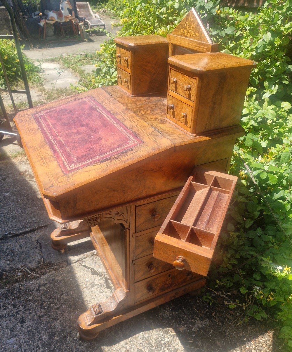 A Victorian burr walnut Davenport desk with a sloped red leather writing surface, inlaid top cresting, and side drawers. View XII