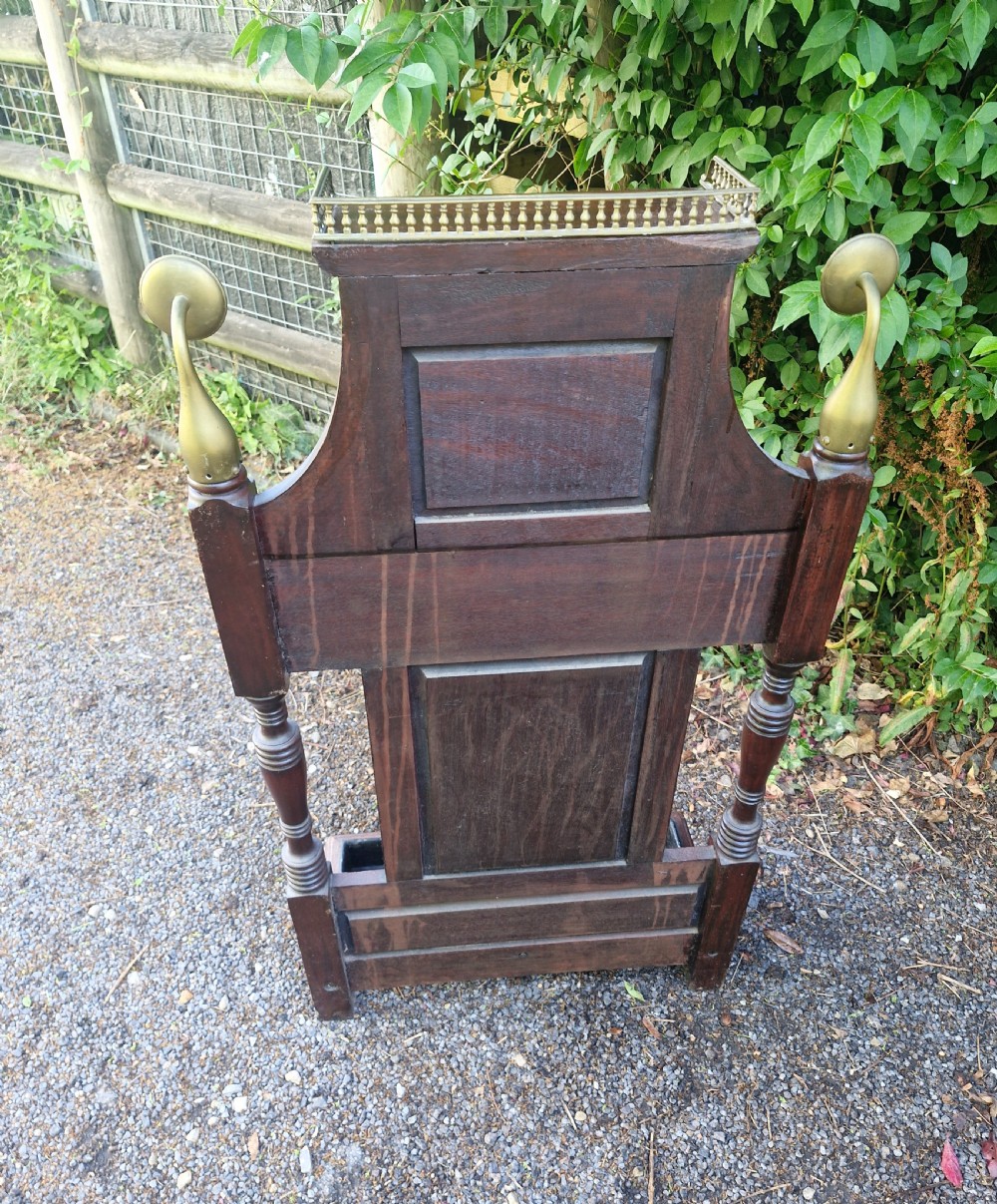 Late Victorian mahogany stick and umbrella stand featuring brass rails, decorative finials, a top gallery shelf, and a cast iron drip tray. View II