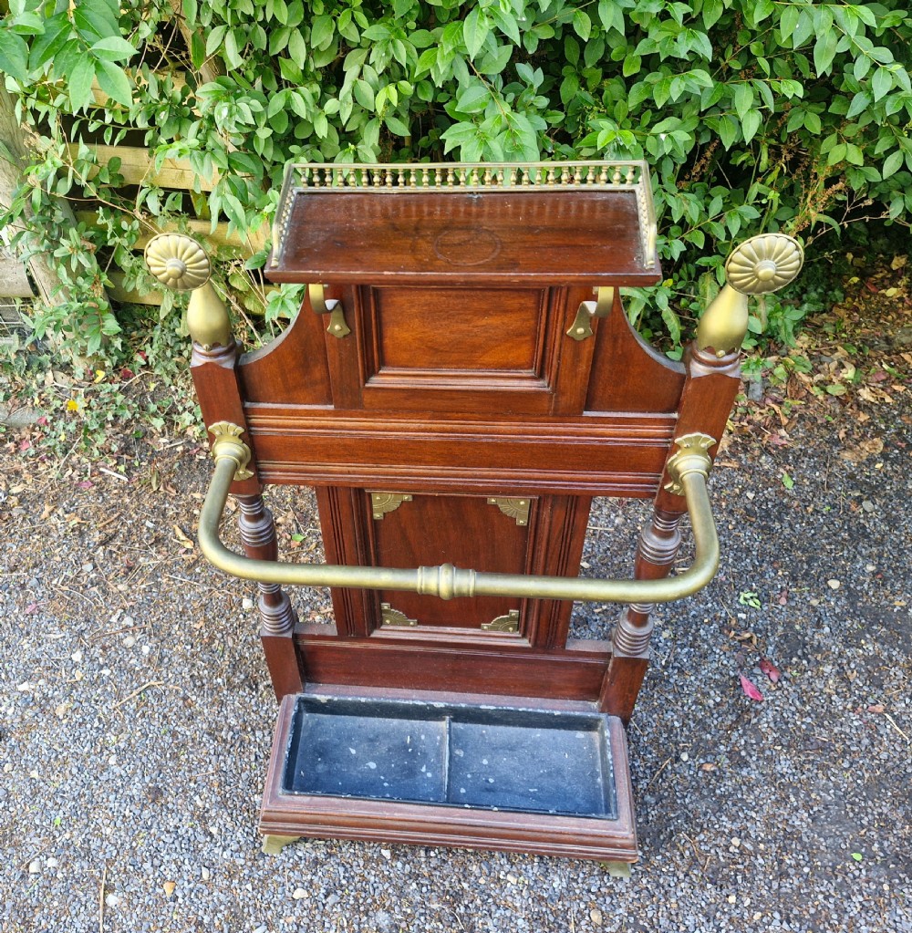 Late Victorian mahogany stick and umbrella stand featuring brass rails, decorative finials, a top gallery shelf, and a cast iron drip tray. View III