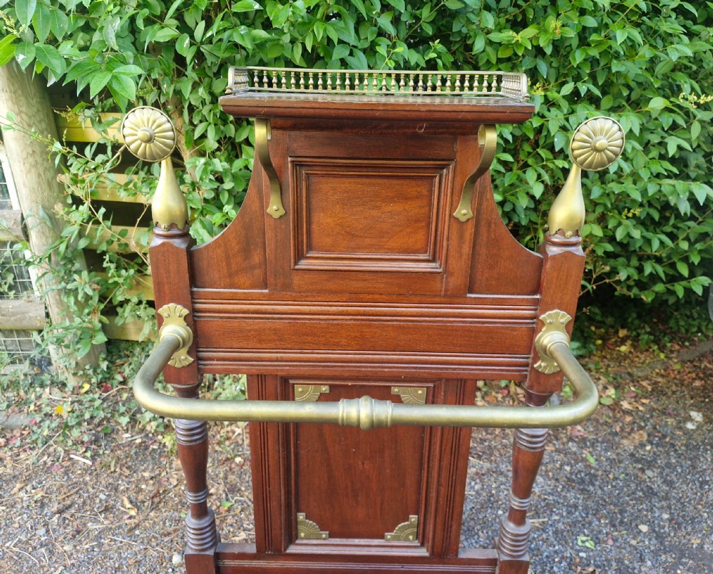 Late Victorian mahogany stick and umbrella stand featuring brass rails, decorative finials, a top gallery shelf, and a cast iron drip tray. View V