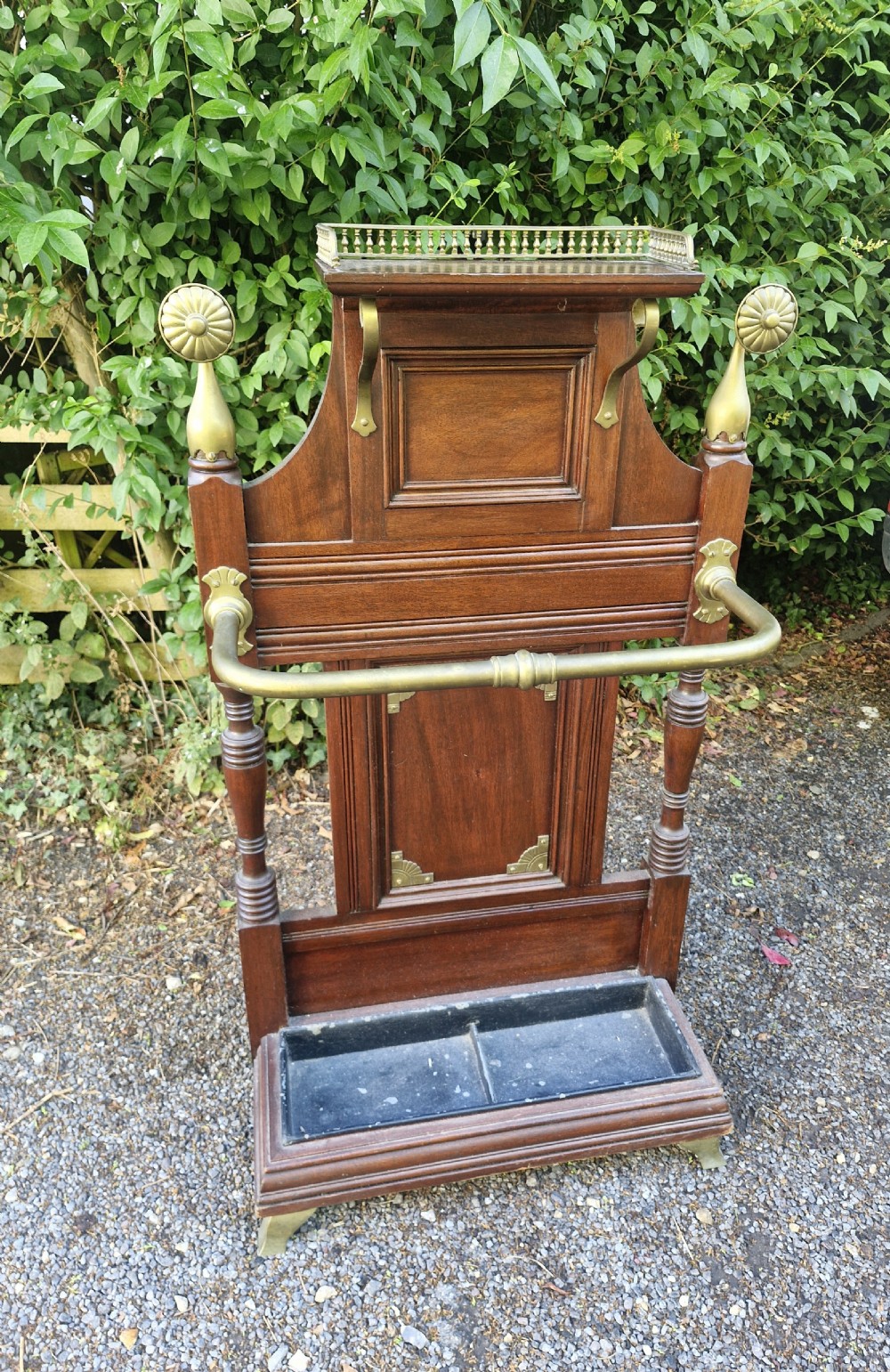 Late Victorian mahogany stick and umbrella stand featuring brass rails, decorative finials, a top gallery shelf, and a cast iron drip tray. View VI