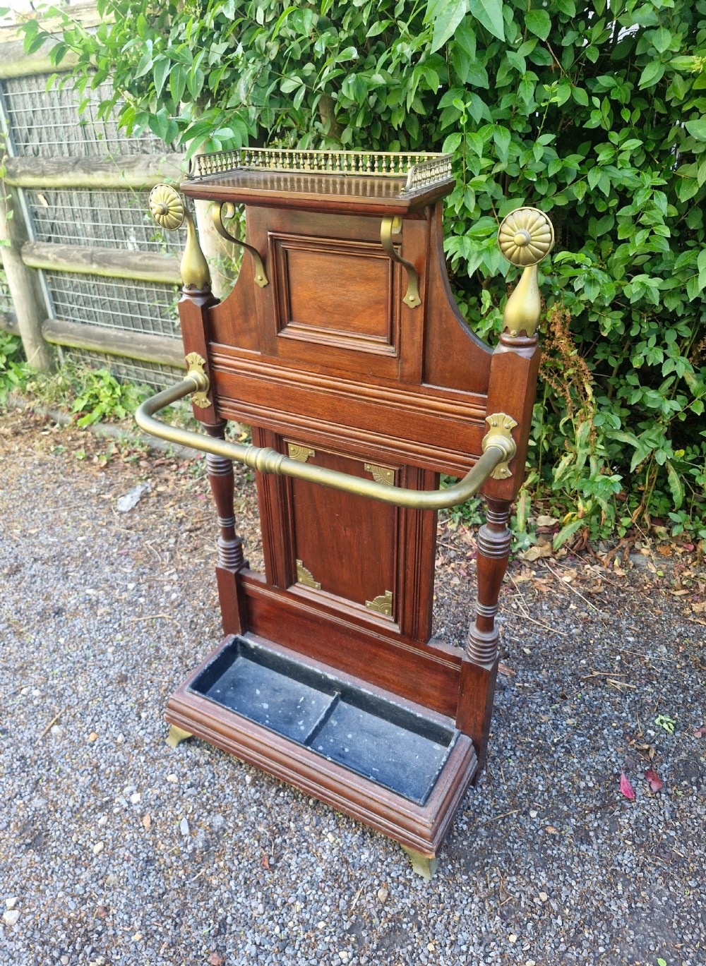 Late Victorian mahogany stick and umbrella stand featuring brass rails, decorative finials, a top gallery shelf, and a cast iron drip tray. View VII