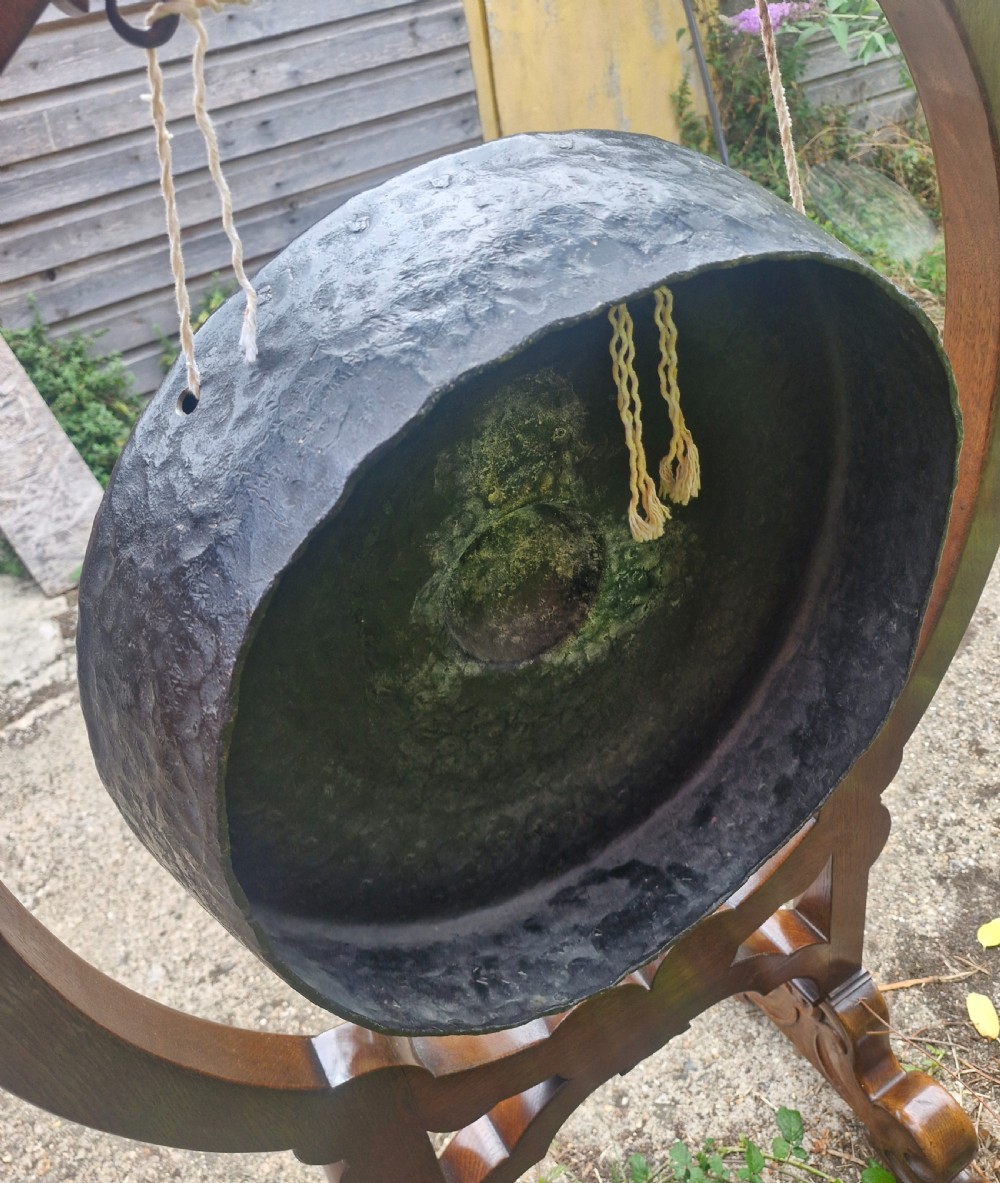 A late Victorian floor-standing dinner gong framed in carved dark oak with a suspended bronze disc. View II