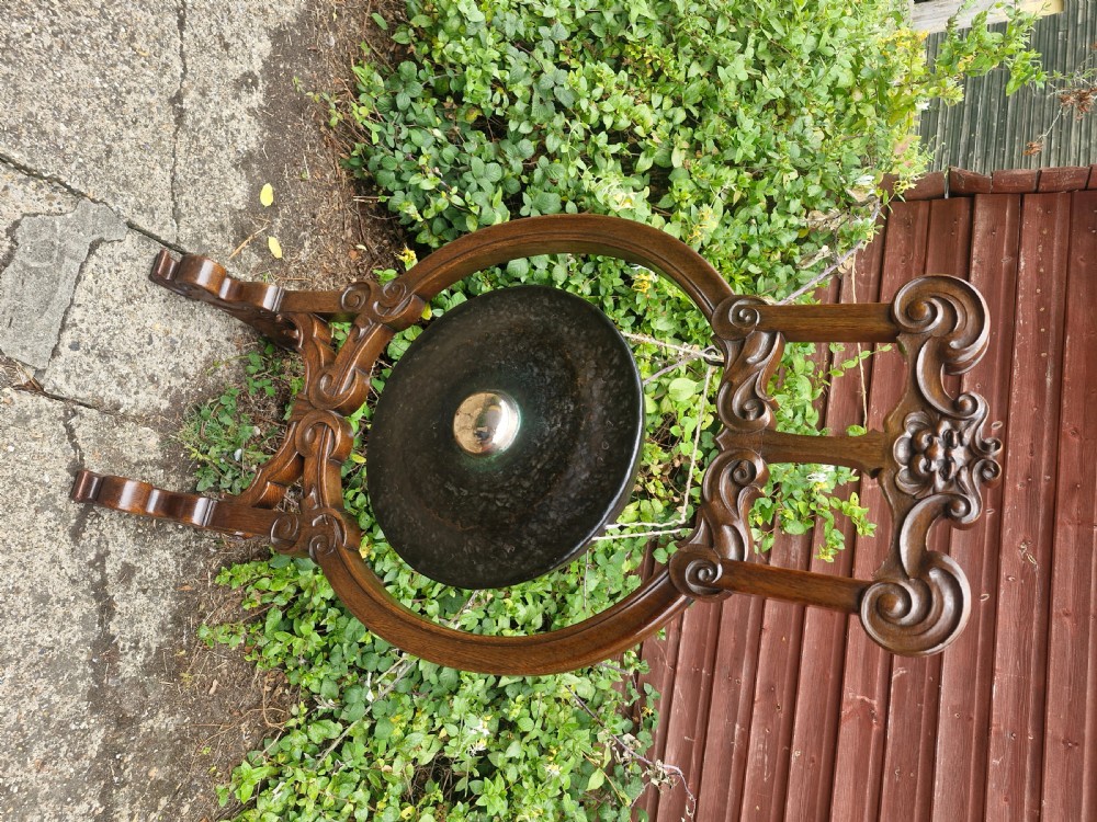 A late Victorian floor-standing dinner gong framed in carved dark oak with a suspended bronze disc. View VII