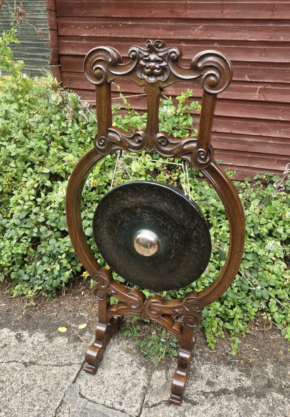 A late Victorian floor-standing dinner gong framed in carved dark oak with a suspended bronze disc. View VIII