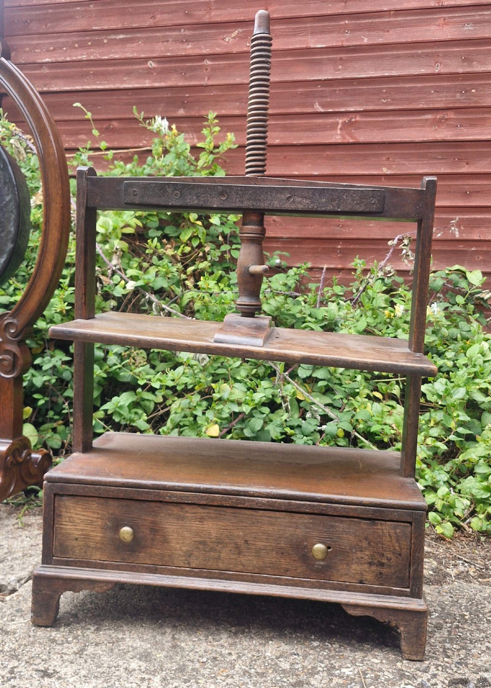 An antique Georgian dark oak tabletop book press featuring a central wooden threaded screw stem, an upper frame, and a base drawer with brass knobs. View III