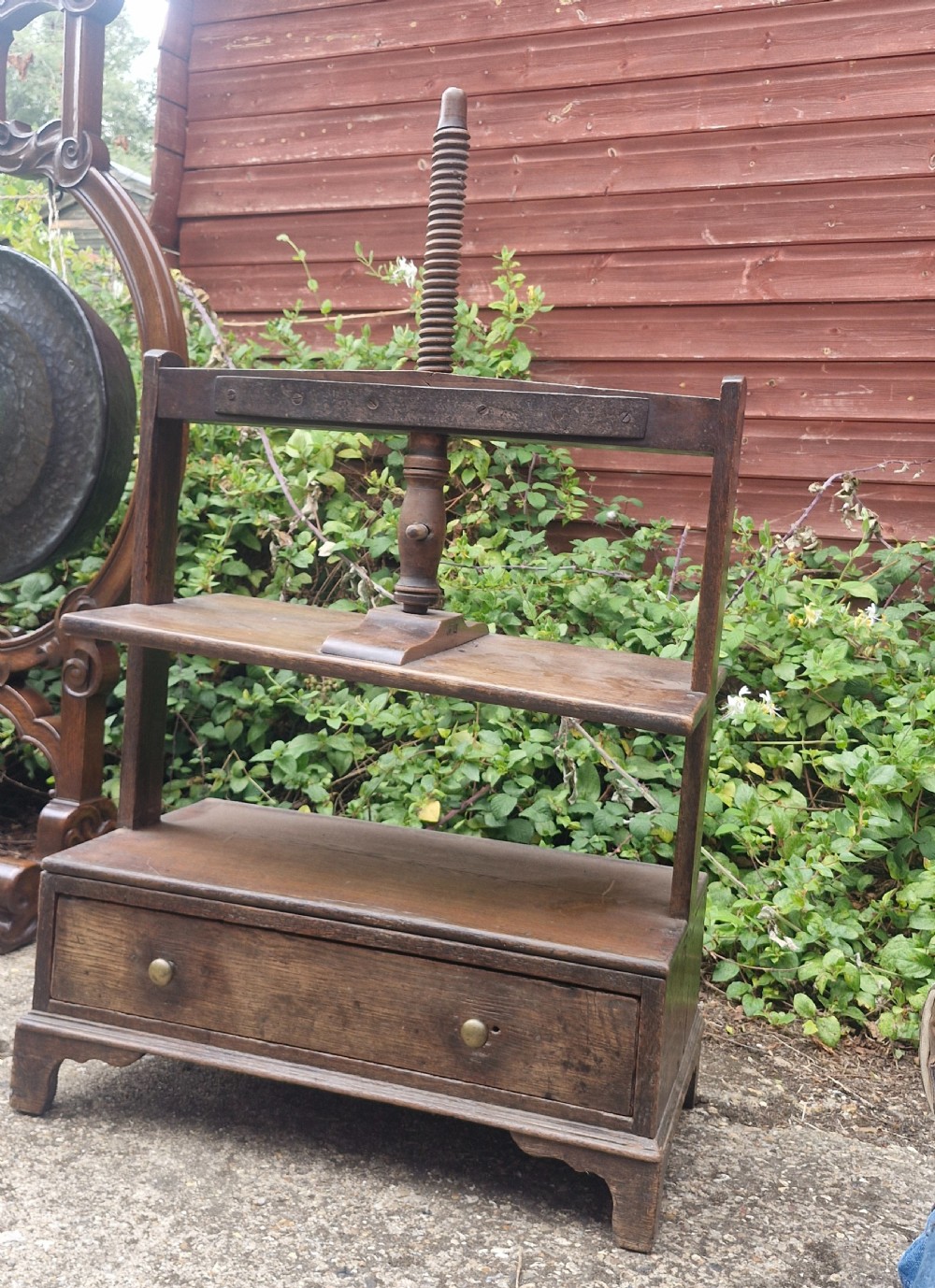 An antique Georgian dark oak tabletop book press featuring a central wooden threaded screw stem, an upper frame, and a base drawer with brass knobs. View VI