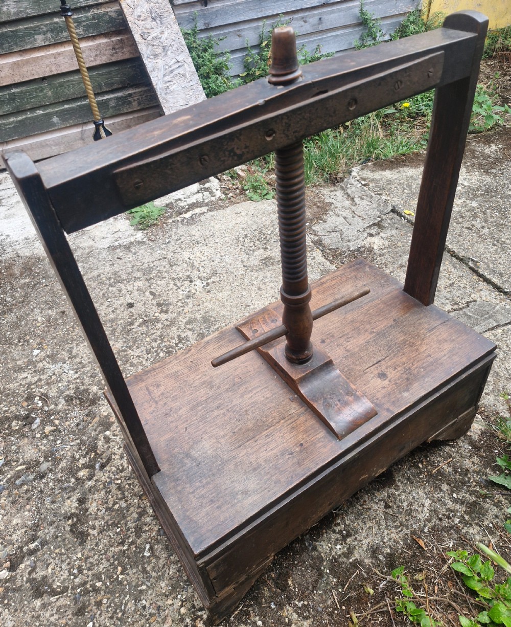 An antique Georgian dark oak tabletop book press featuring a central wooden threaded screw stem, an upper frame, and a base drawer with brass knobs. View VII