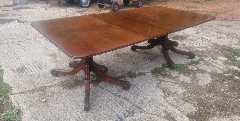 A Regency mahogany double pedestal dining table with a rounded rectangular top and carved splayed legs, fitted with an additional leaf.