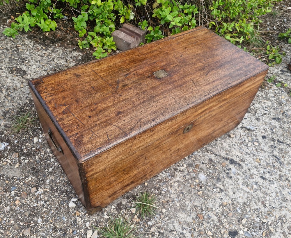 An early 20th century rectangular teak trunk featuring a hinged lid, a central metal lockplate, and side carrying handles. View II