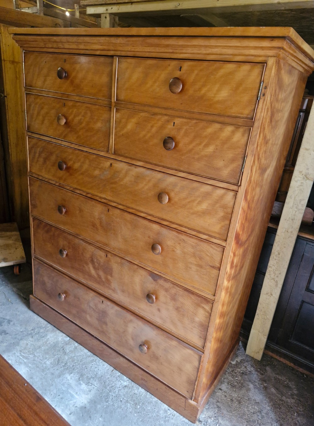An oversized Victorian satinbirch chest of drawers featuring flame-figured wood grain, turned wooden knobs, and a solid plinth base. View VI