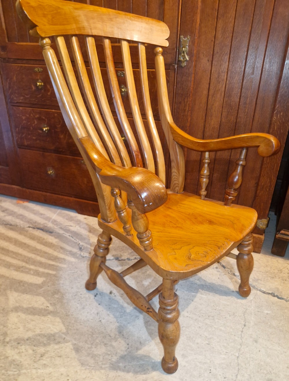 A Victorian wooden Windsor armchair featuring a shaped crest rail, vertical spindles, a contoured saddle seat, curved armrests, and turned legs. View II