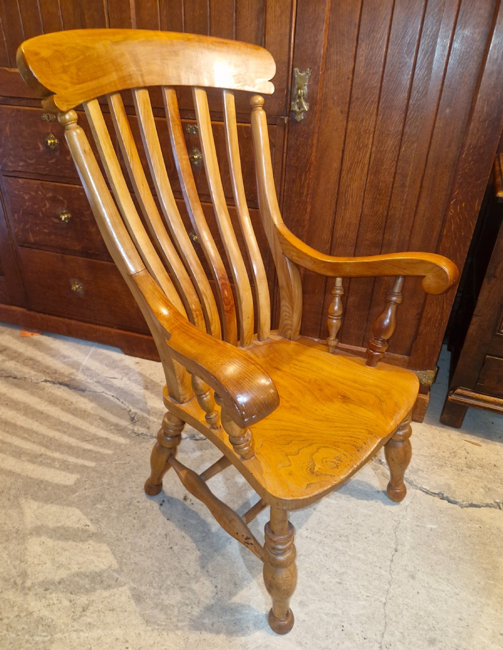 A Victorian wooden Windsor armchair featuring a shaped crest rail, vertical spindles, a contoured saddle seat, curved armrests, and turned legs. View III